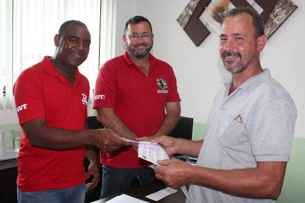Valdir e o presidente Herivelto Vela entregam cheque de pagamento a Raimundo Nogueira, que ficou 13 anos exposto às más condições de trabalho